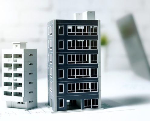 businessman working on laptop in office with building models on table