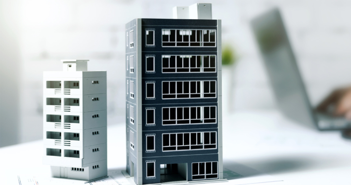 businessman working on laptop in office with building models on table