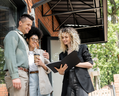 smiling real estate agent showing documents to interracial couple