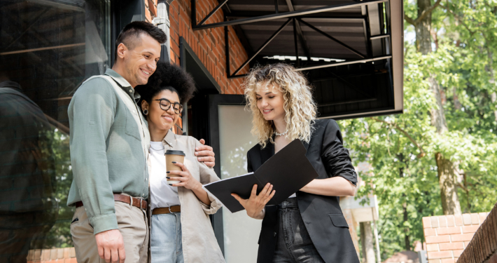 smiling real estate agent showing documents to interracial couple