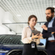 two people talk infront of car